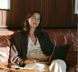 A woman working on a laptop, relaxed on a couch